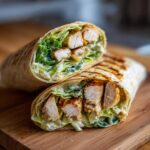 Close-up van twee helften van Chicken Caesar Wraps gevuld met gegrilde kipstukjes, sla en Caesar dressing.