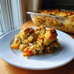 Een portie Chicken Stuffing Casserole met een goudbruine, knapperige topping op een wit bord.