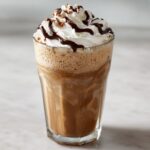 Hoog glas met een romige Chocolate And Vanilla Eiskaffee, afgetopt met slagroom en chocoladesiroop.