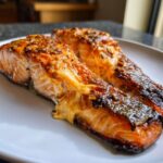 Twee stukken perfect gebakken Creamy Cajun Stuffed Salmon op een wit bord.