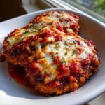 Twee porties Eggplant Parmesan bedekt met rijke tomatensaus en gesmolten mozzarella, gegarneerd met peterselie.