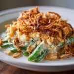 Een close-up van een portie Green Bean Casserole met romige saus en krokante gebakken uitjes.
