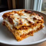 Close-up van een dikke laag Chicken Bolognese Lasagna met gesmolten, gebruinde kaas bovenop.
