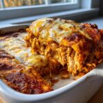 Een schep rijkelijk gevulde Kip Enchiladas met draadjes kip en gesmolten, bubbelende kaas.