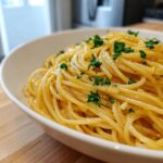 Close-up van een witte kom gevuld met romige Lemon Pasta, gegarneerd met verse groene peterselie.