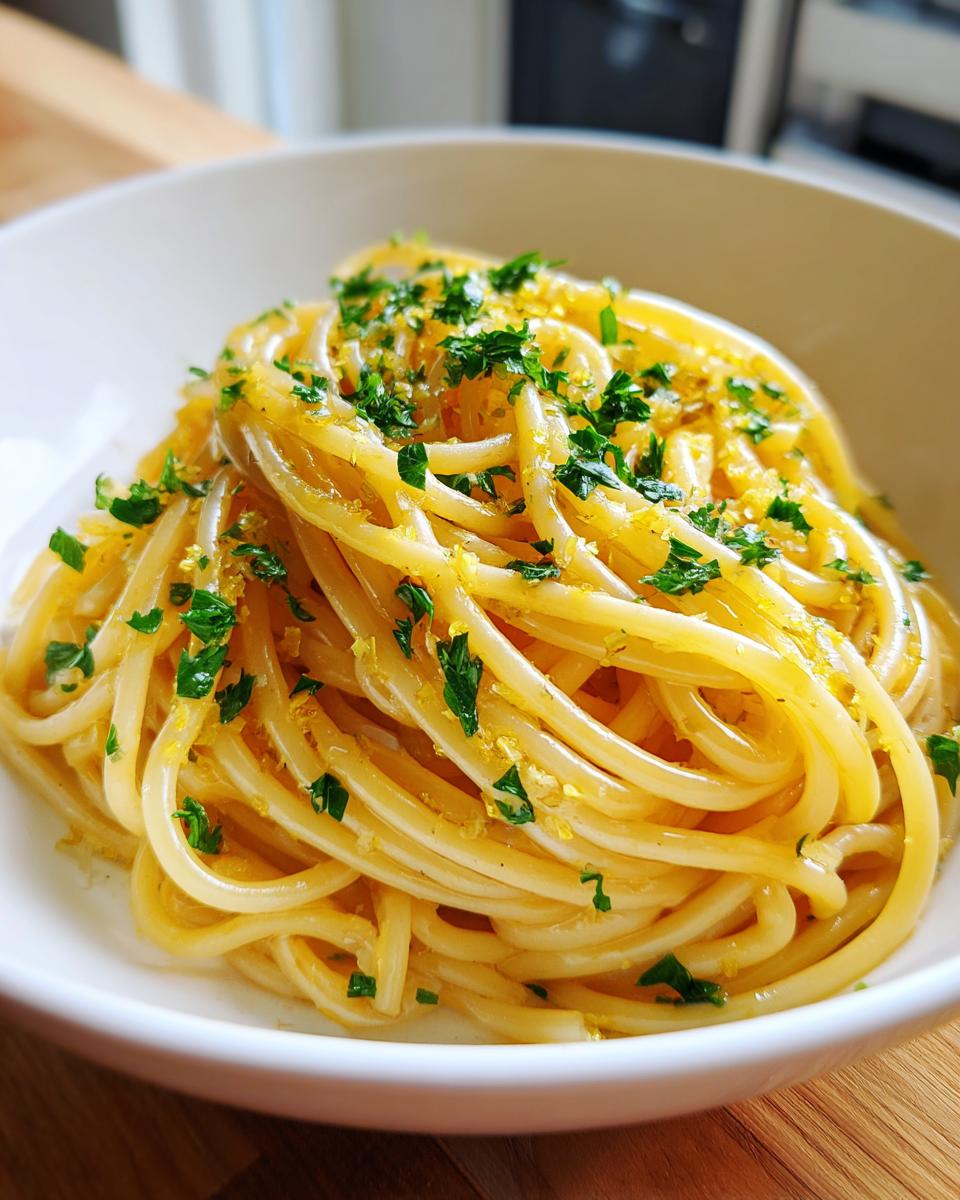 Close-up van een portie romige Lemon Pasta, gegarneerd met citroenrasp en verse peterselie.