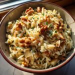 Close-up van een kom Orzo Salade Met Peren Walnoten En Gorgonzola, gegarneerd met walnoten en peterselie.