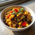 Close-up van een kom met Quinoa Southwestern Salad, gevuld met ma&iuml;s, zwarte bonen en rode paprika.