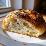 Close-up van een doorsnede van Rosemary Garlic No Knead Skillet Bread met een goudbruine, knapperige korst en luchtige binnenkant.