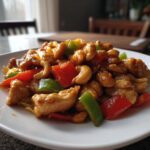 Close-up van een portie Skinny Cashew Chicken met stukjes kip, cashewnoten en kleurrijke paprika.