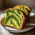 Drie dikke plakken Slow Cooker Basil Pesto Brood met een prachtig groen pesto-marmerpatroon op een wit bord.