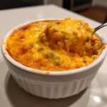 Een lepel haalt een romige hap uit de Slow Cooker Smoked Sausage Cheddar Cheese Dip met gesmolten kaas.