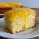 Een dikke snee citroencake met een glanzende, druipende laag Lemon Curd Topped Lemon Cake.