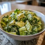 Close-up van een kom met de romige Tiktok Green Goddess Salad, vol met sla, avocado en komkommer.