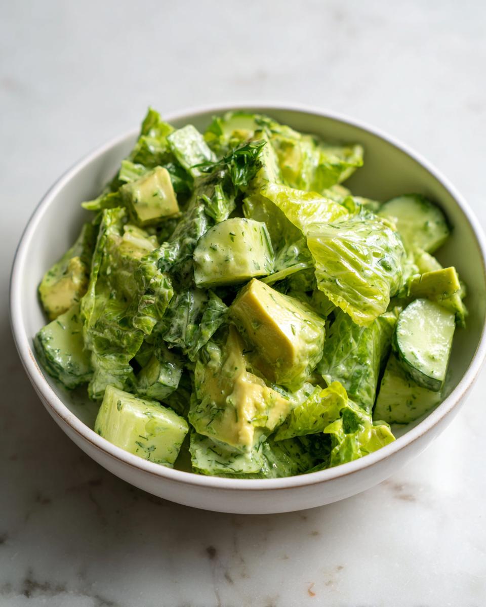 Een kom met de romige Tiktok Green Goddess Salad, vol sla, avocado en komkommerblokjes.