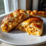 Een doormidden gesneden Buffalo Chicken Crescent Roll met een vulling van gekruid kippenvlees.