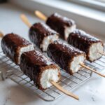 Zes heerlijke chocolade overgoten marshmallow lolly's die afkoelen op een metalen rooster.