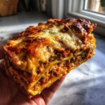 Een dikke laag Easy Eggplant Lasagna met een goudbruin gegratineerd kaaskorstje wordt vastgehouden.