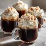 Close-up van vier glazen met rijke Mexicaanse Koffie, afgetopt met toefen slagroom en kaneel.