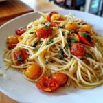 Close-up van een bord met Jennifer Garners 5 Ingredient Pasta, gegarneerd met geroosterde cherrytomaten en verse kruiden.