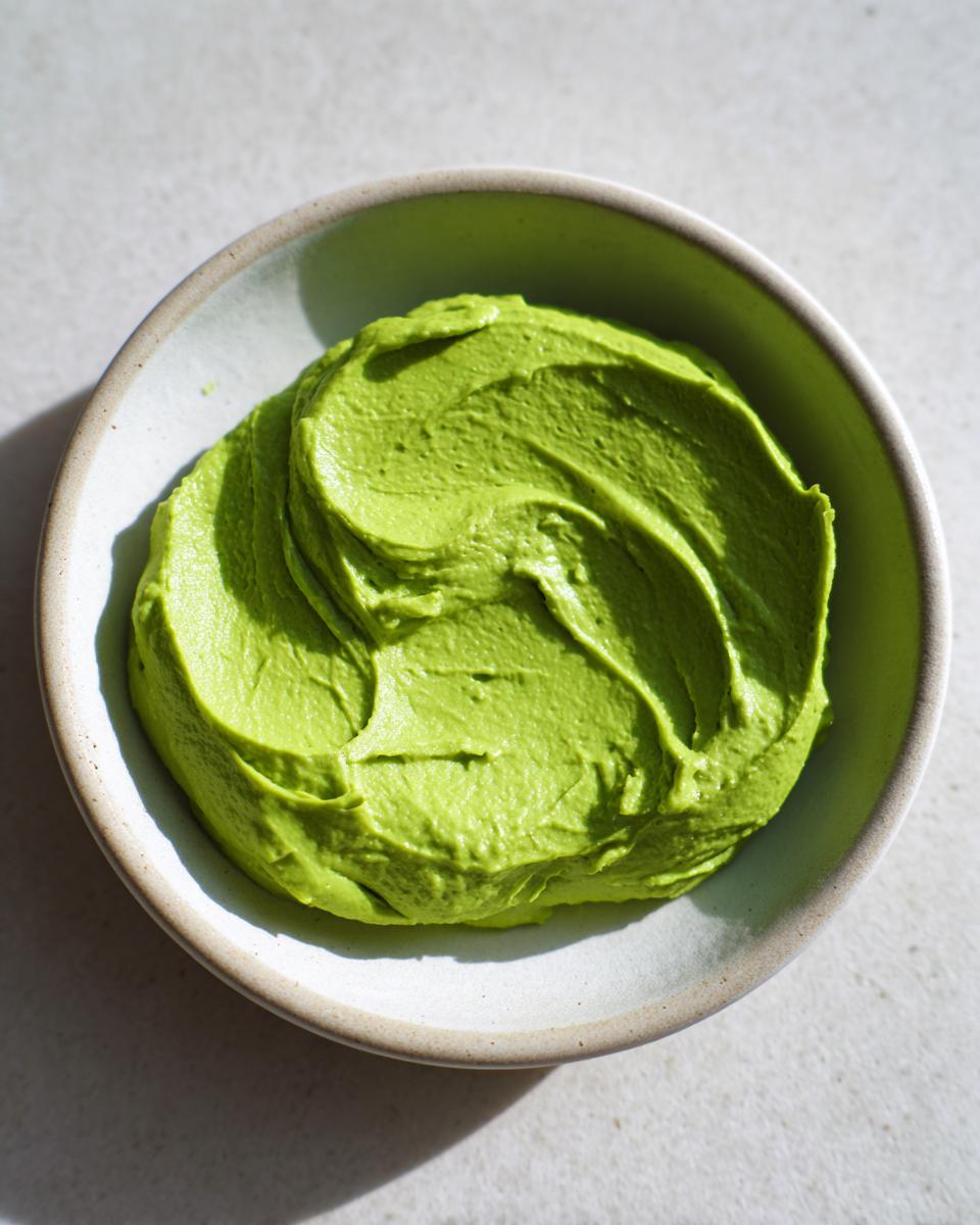 Een kom met felgroene, gladde Lichte Romige Avocado Limoen Saladedressing, gefotografeerd van bovenaf.