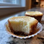 Close-up van een Low Carb Cheesecake Bite met een hap eruit, toont de romige vulling en de bodem.