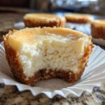 Close-up van een Low Carb Cheesecake Bite met een hap eruit, in een papieren vormpje.