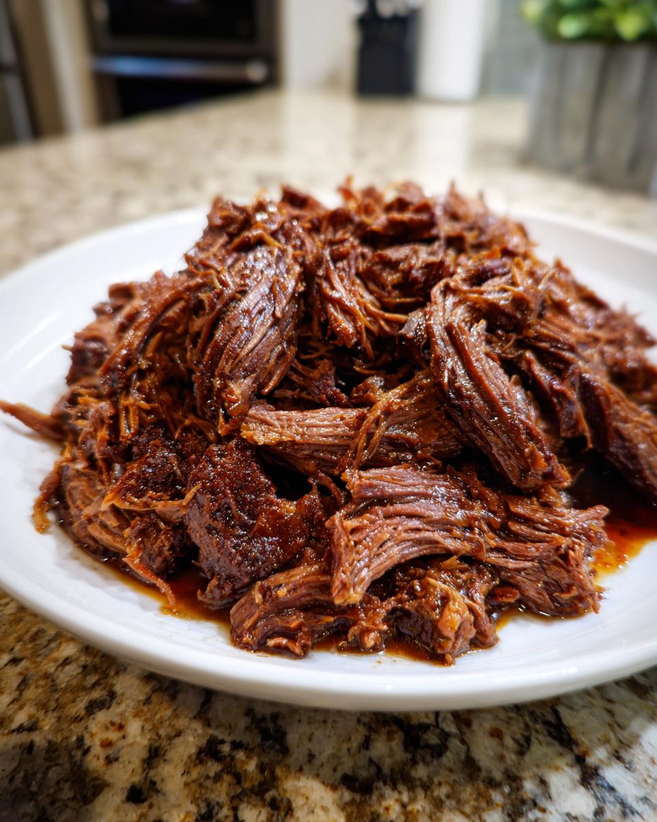 Een close-up van heerlijk mals, draadjesvlees Slow Cooker Beef Barbacoa op een wit bord.