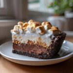 Een dikke plak Mississippi Mud Pie met een donkere koekbodem, chocoladevulling en geroosterde marshmallows bovenop.