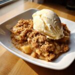 Een portie Old Fashioned Apple Crisp met een bol romig vanille-ijs erop.