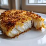 Close-up van een stuk krokante Parmesan Crusted Tilapia met wit, schilferig visvlees.