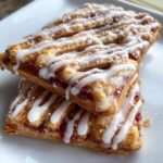 Twee gestapelde Phyllo Raspberry Pop Tarts met een dikke witte vanille glazuur.