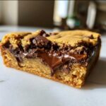 Close-up van een zachte Peanut Butter Chocolate Chip Cookie Bar met smeltende chocolade.