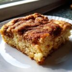 Een close-up van een stuk Snickerdoodle Cobbler met een dikke, gekruide kaneel-suiker topping op een wit bord.