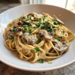 Close-up van een kom met romige miso champignon pasta, gegarneerd met verse peterselie.