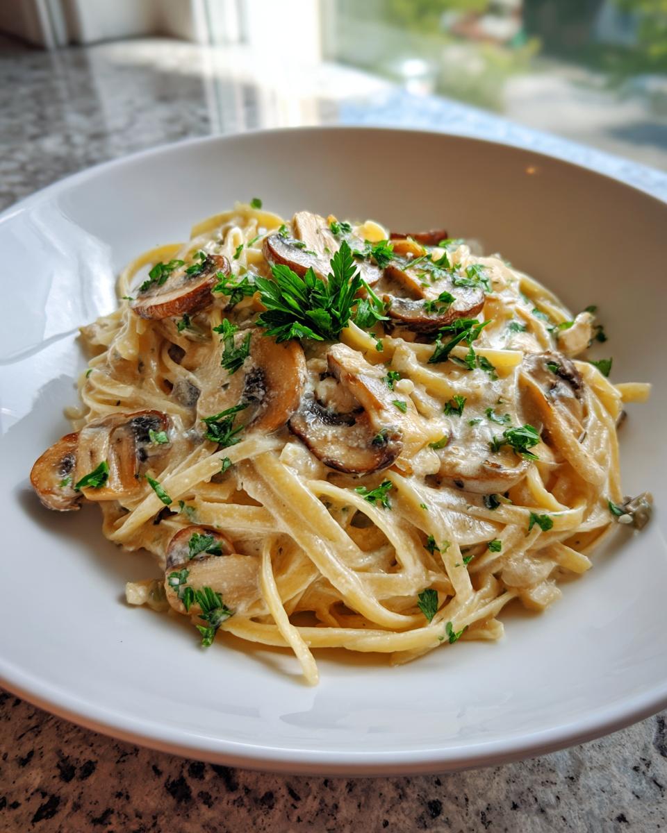 Close-up van romige Miso Champignon Pasta met gebakken champignons en peterselie in een witte kom.