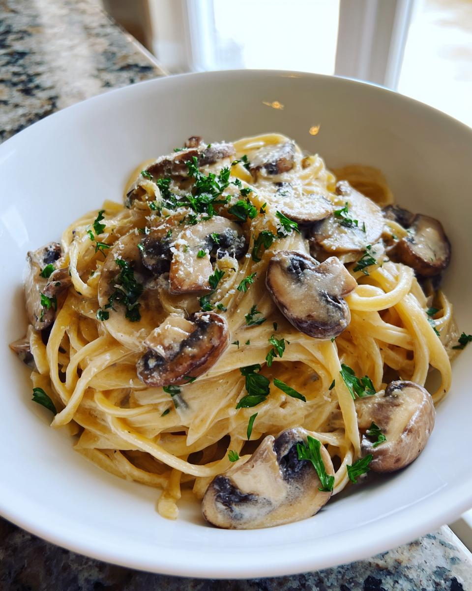 Close-up van een kom met romige Miso Champignon Pasta, gegarneerd met plakjes champignons en peterselie.