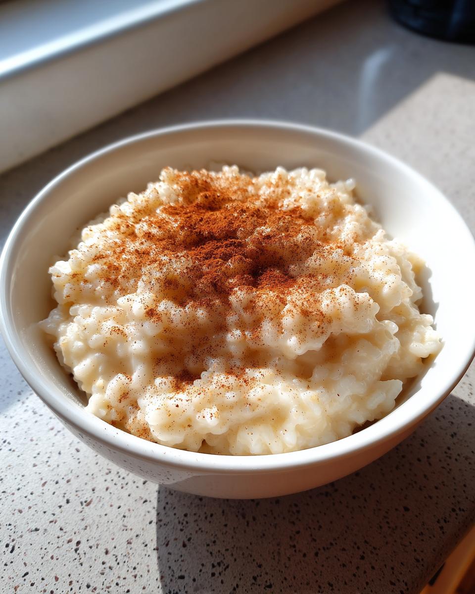 Een kom romige rijstepap, royaal bestrooid met kaneel, gefotografeerd in natuurlijk licht.