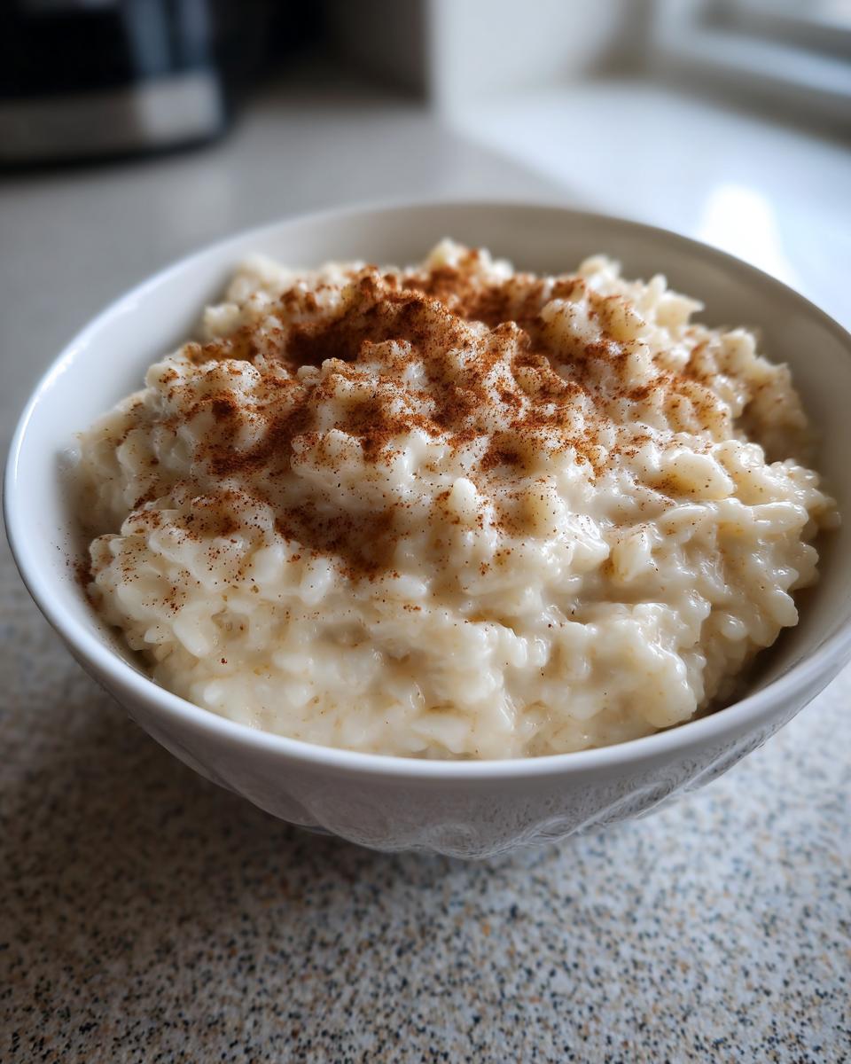 Close-up van een kom met romige rijstpap, rijkelijk bestrooid met kaneel.