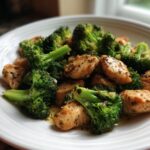 Close-up of seasoned, pan-seared chicken pieces mixed with bright green steamed broccoli florets, served as a Chicken Broccoli Dinner.