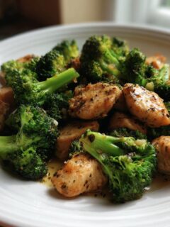 Close-up of seasoned, pan-seared chicken pieces mixed with bright green steamed broccoli florets, served as a Chicken Broccoli Dinner.