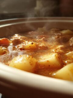 Close-up of steaming Chicken Potato Soup with chunks of chicken and potatoes in a savory broth.